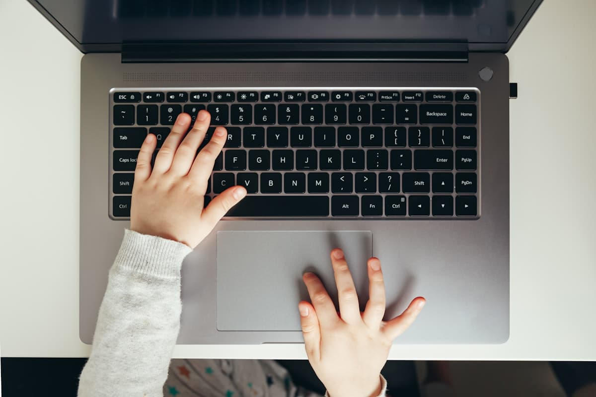 Manos de una niña sobre el teclado de una computadora portátil